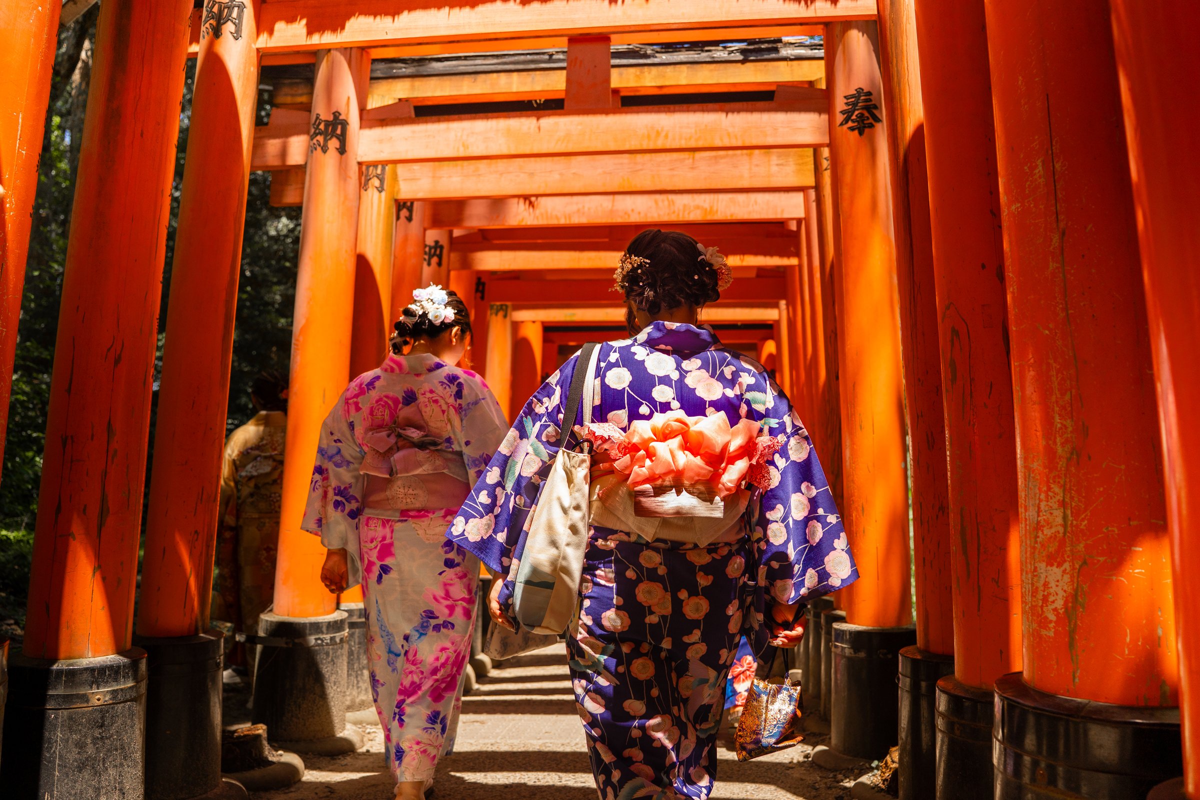 Two women in kimonos walking through torii gates